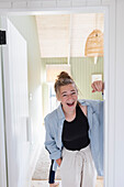 Portrait of teenage girl (16-17) standing in doorway and laughing