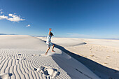 United States, New Mexico, White Sands National Park, Boy (10-11) leaping on sand dunes