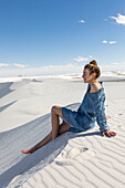 Vereinigte Staaten, New Mexico, White Sands National Park, Jugendliches Mädchen sitzt auf Sand
