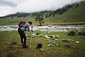 Russland, Karatschai-Tscherkessien, Arkhyz, Kaukasusgebirge, Wanderer fotografiert mit Stativ im nebligen Gebirge