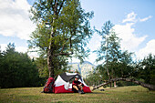 Russia , Karachay-Cherkessia, Arkhyz, Caucasus mountains, Hiker sitting by tent in mountains