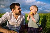 Vater mit kleinem Sohn (12-17 Monate) auf einem landwirtschaftlichen Feld