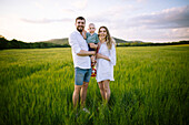 Portrait of parents with baby son (12-17 months) in agricultural field