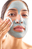 Nahaufnahme einer Frau, die eine blaue Gesichtsmaske abnimmt