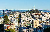 San Francisco, California, hills of the city and Coit Tower in sunshine with streets and bridges in the background from Lombard Street