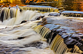 Gelb- und Goldtöne spiegeln sich im Middle Branch des Ontonagon River an der Bond Falls Scenic Site, Michigan, USA