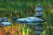 Concrete lantern on a rock in a pond surrounded by reflections of Fall colors in the water, Japanese Garden, Washington Park Arboretum, Seattle, Washington State