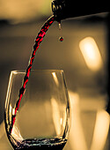 Ein Tropfen zeigt sich, als der Rotwein ins Glas gegossen wird.