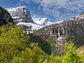 Blick auf einen Wasserfall an einer steilen Bergwand mit dem Myklebustbreen-Gletscher an der Spitze, Vestland, Norwegen, Skandinavien, Europa