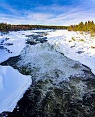 Cold rapids of waterfall running fast through the snowy Arctic forest, Jockfall, Overkalix, Norrbotten county, Lapland, Sweden, Scandinavia, Europe