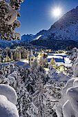 Vollmond über der schneebedeckten Chiesa Bianca, umgeben von Wäldern, Maloja, Bergell, Engadin, Kanton Graubünden, Schweiz, Europa
