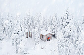 Aerial view of happy couple enjoying the winter holidays in a frozen hut in the snowy forest, Iso Syote, Northern Ostrobothnia, Lapland, Finland, Europe