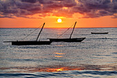 Bewölkter Himmel bei Sonnenaufgang über Silhouetten von im Meer vertäuten Booten, Jambiani, Sansibar, Tansania, Ostafrika, Afrika
