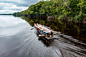 Illegale Bergleute auf ihrem Boot auf dem schwarzen Pasimoni-Fluss, im tiefen Süden von Venezuela, Südamerika