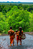 Couple with their child, standing on a giant rock, Yanomami tribe, southern Venezuela, South America