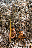 Young boys looking through a hole, Yanomami tribe, southern Venezuela, South America