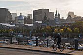 Radfahrer fährt entlang des alten Hafens von Montreal mit historischen Gebäuden im Hintergrund, Montreal, Québec, Kanada, Nordamerika