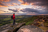 Ein männlicher Wanderer steht bei Sonnenuntergang auf Curbar Edge, Peak District, Derbyshire, England, Vereinigtes Königreich, Europa