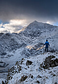 Wanderer mit Blick auf den Mount Snowdon (Yr Wyddfa) im Winter, Snowdonia National Park, Eryri, Nordwales, Vereinigtes Königreich, Europa