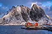 Red Norwegian Rorbuer Cabins and Festhaeltinden mountain in winter, Reine, Moskenes Municipality, Nordland County, Lofoten Islands, Norway, Scandinavia, Europe
