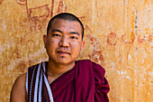 Portrait of monk looking at camera in front of temple, Bagan, Myanmar (Burma), Asia