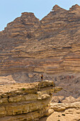 Man standing on cliff against mountains, Wadi Sinaq, Dhofar Governorate, Oman, Middle East