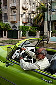 Fahrer in grünem Chevrolet-Oldtimer mit offenem Verdeck, geparkt in einem Vorort, Havanna, Kuba, Westindien, Karibik, Mittelamerika