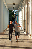 Two good friends walking down a colonnade, Cienfuegos, Cuba, West Indies, Caribbean, Central America