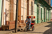 Bicycle buggy named Ferrari going down a cobblestone street, Trinidad, Cuba, West Indies, Caribbean, Central America