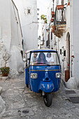 Blaues Touristen-Tuk-Tuk beim Sightseeing durch die engen Gassen der alten weißen Stadt, Ostuni, Provinz Brindisi, Apulien, Italien, Europa