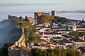 View over the old town and walls of Obidos in morning mist, Obidos, Centro Region, Estremadura, Portugal, Europe