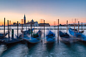 Die venezianischen Gondeln an der Riva degli Schiavoni und im Hintergrund die St. Georgs Kirche bei Sonnenaufgang, Venedig, Venetien, Italien, Europa