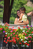 Mom and daughter embrace and look panorama from the wooden bridge (Ponte di Legno di Pellizzano) in a summer time, Pellizzano, Sole valley (val di Sole), Trento province, Trentino-Alto Adige, Italy, Europe (MR)