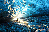 one hiker admiring one ice cave in Jokusarlon Glacier Lagoon area in winter time, Austurland, Iceland, Europe