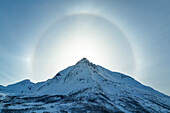 Drohnenaufnahme einer Sonneneruption um einen Berggipfel, Troms, Norwegen, Europa