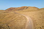 aerial view taken by drone of the volcanic area near to Corralejo during a summer sunset with a girl along the road, Natural Park of Corralejo, Fuerteventura, Canary Island, Spain, Europe