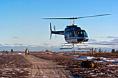 A helicopter delivers barrels of fuel.