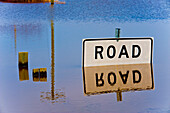 Road closed sign reflected in flood waters.