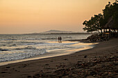 Couple walking at sunset in Jiquilillo beach, Chinandega, Nicaragua