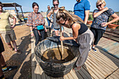 Woman stirs healing mud at salt marshes, Isla Cristina, Spain