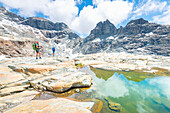 Hikers at Gran Lac de Tzere, Vallone delle Cime Bianche, Val d Ayas, Italian alps, Aosta valley, Italy