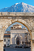 Sulmona, die Kirche San Filippo, gesehen durch die Bögen des mittelalterlichen Aquädukts. Im Hintergrund der schneebedeckte Berg von Morrone. Sulmona, Provinz von L'Aquila, Abruzzen, Italien, Europa