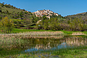 Das kleine Bergdorf San Benedetto in Perillis. Im Vordergrund ein Teich in der Talsohle mit Schilf und Weiden. Abruzzen, Italien