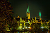 Die Glockentürme der St. Petri-Kirche und des Lübecker Doms, die alten Häuser über der Trave, die an einem Sommerabend von künstlichen Lichtern beleuchtet werden. Lübeck, Land Schleswig-Holstein, Deutschland
