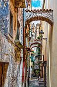 Charakteristische enge Gasse zwischen hohen Gebäuden mit Stützbögen zwischen den Häusern. Vico del Gargano, Provinz von Foggia, Apulien, Italien