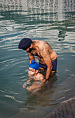 pilgrims (father and daughter) bathing in the sacred pool Amrit Sarovar, Golden temple, Amritsar, Punjab, India