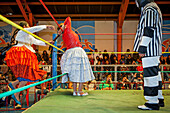 Lucha Libre. Combat between Dina with orange skirt and Benita la Intocable , cholitas females wrestlers ,with referee, Sports center La Ceja, El Alto, La Paz, Bolivia