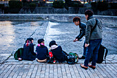 Männer im Gespräch mit Mädchen, Kamo-Fluss in Pontocho, Kyoto, Japan