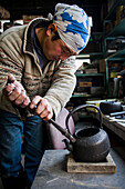 Takahiro Koizumiis putting the handle at iron teapot or tetsubin, nanbu tekki, Workshop of Koizumi family,craftsmen since 1659, Morioka, Iwate Prefecture, Japan