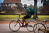 Mann beim Radfahren im Wat Mahathat, Sukhothai Historical Park, Sukhothai, Thailand
